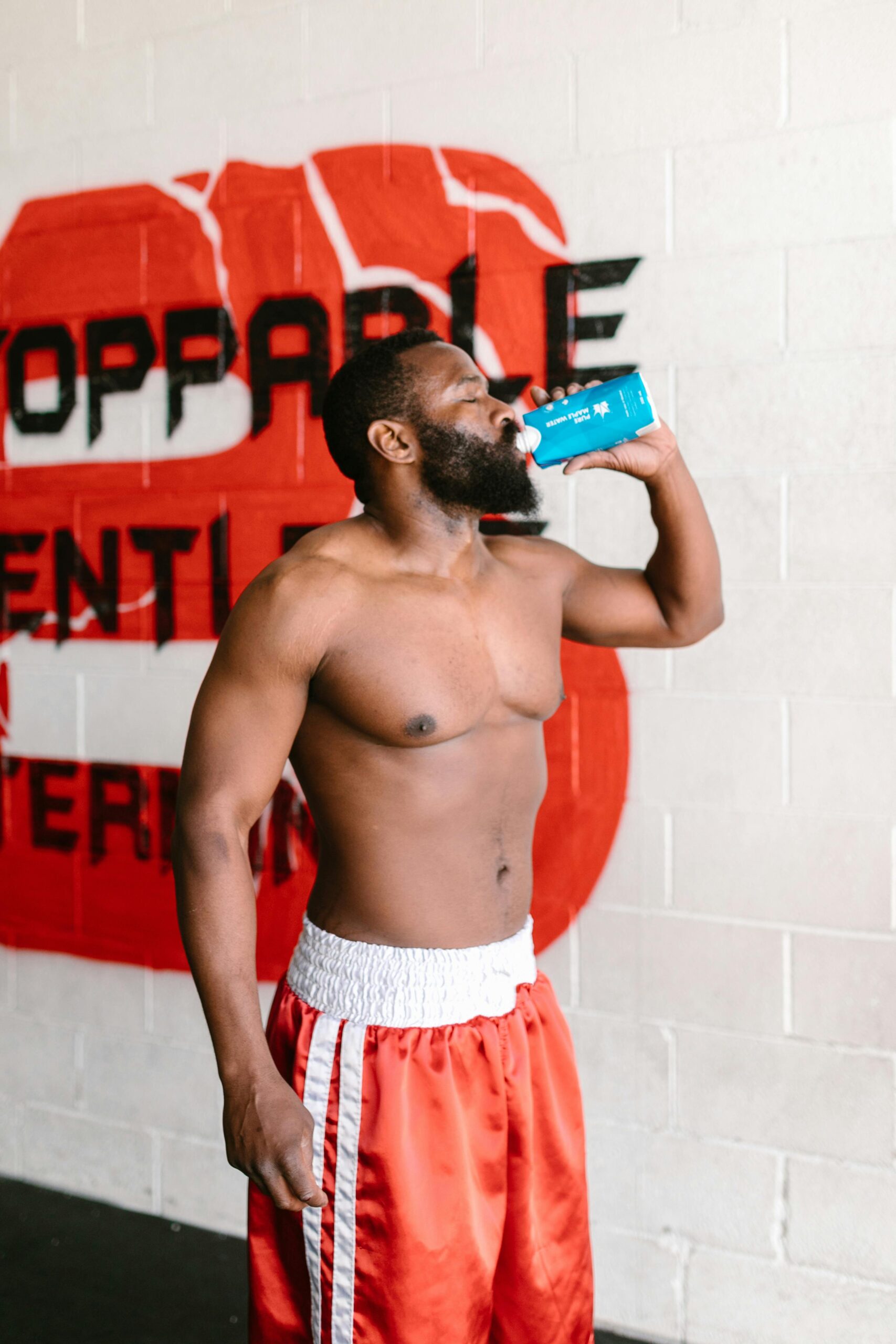Male boxer drinking sports hydration drink after training for post-workout recovery and weight management